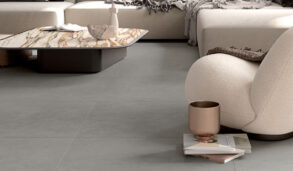 Detaljbilde av stue med flislagt gulv og komfortabel sofa med myke tekstiler